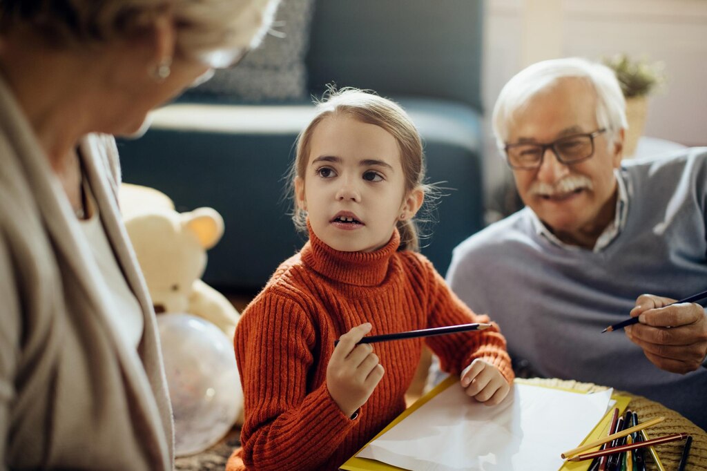 Little girl talking to grandparents while drawing on the paper at home